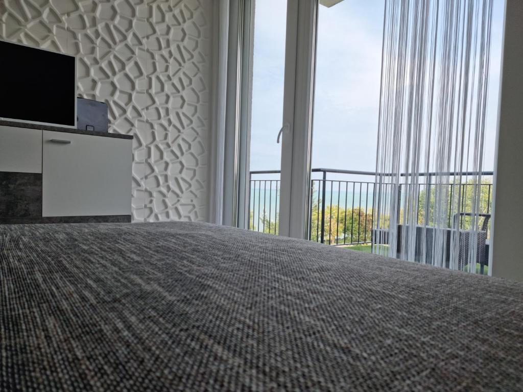 sypialnia z łóżkiem, telewizorem i balkonem w obiekcie Best Panoráma Apartman w Siófoku
