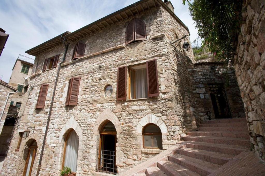 un ancien bâtiment en pierre avec des escaliers menant à celui-ci. dans l'établissement Hotel La Fortezza, à Assise
