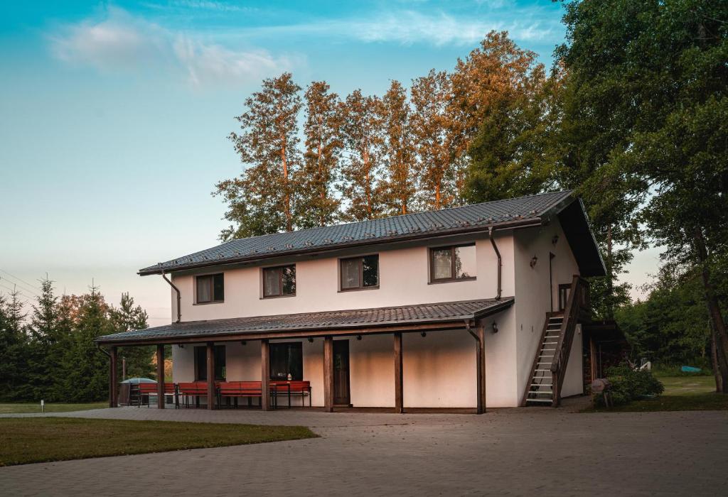 ein großes weißes Haus mit einer Veranda und einem Tisch in der Unterkunft Vėjo Malūnų sodyba - vila in Paserninkai