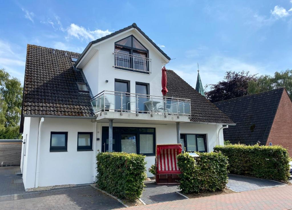 a white house with a balcony and a red chair at Haus Cathleen Wohnung 1 in Dahme