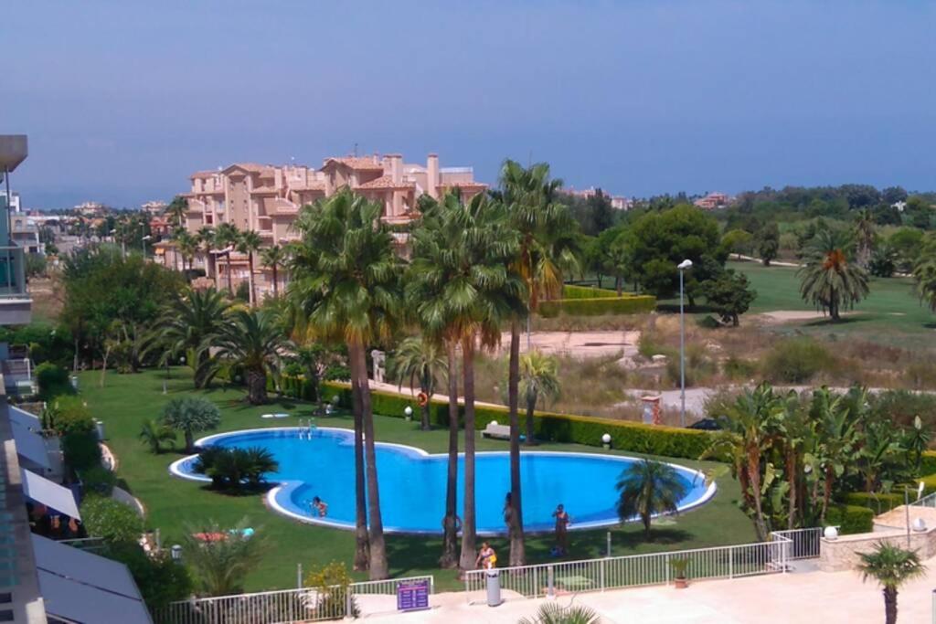 a view of a pool with palm trees and buildings at Brisa de Mar en Oliva Nova, junto a MET y golf in Oliva