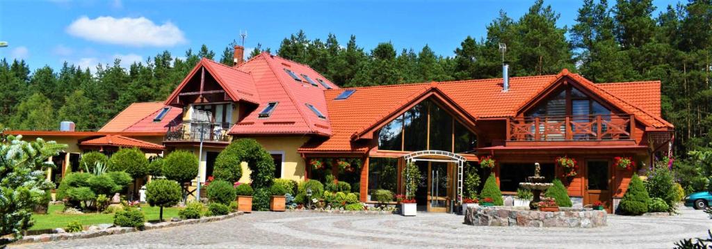 una grande casa in legno con tetto rosso di Agroturystyka Żabi Dwór a Ostrzyce