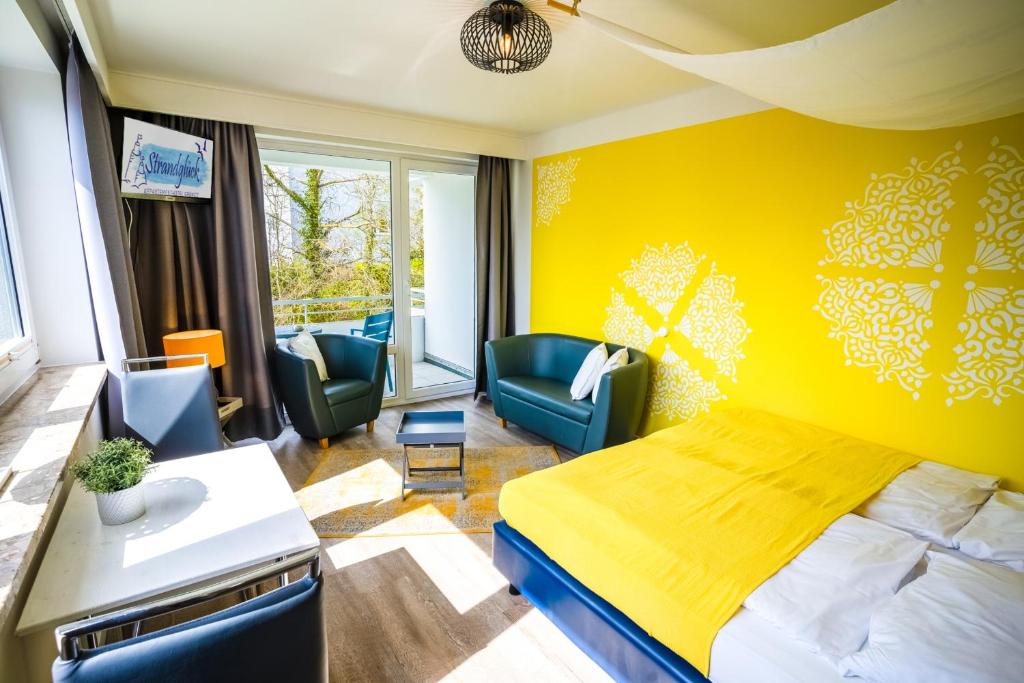 a hotel room with a yellow bed and chairs at Studio 41 "Sonnenschein" in Grömitz