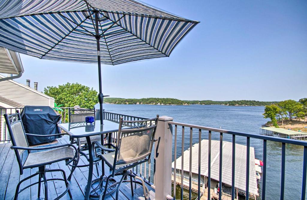a table with chairs and an umbrella on a balcony at Waterfront Ozark Gem with Pool Access and Lake Views! in Lake Ozark