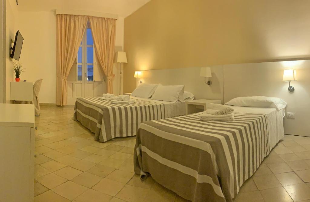 pokój hotelowy z dwoma łóżkami i oknem w obiekcie Nuova Mastrarua Rooms w Syrakuzach