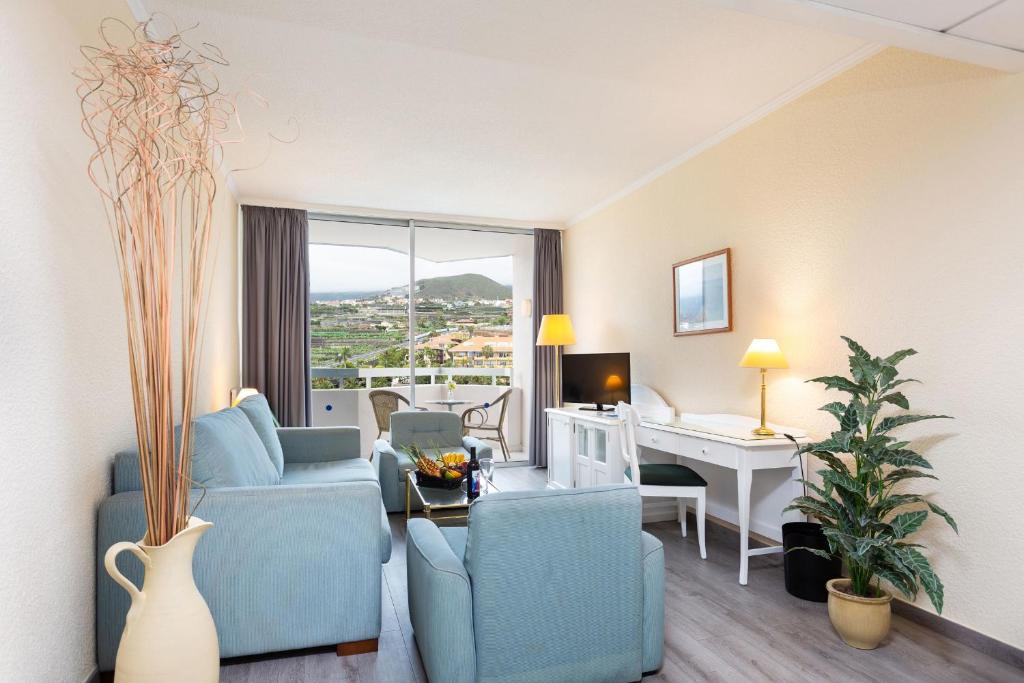 プエルト・デ・ラ・クルスにあるApartment 825 im Precise Resort Tenerifeのリビングルーム(青い椅子、テーブル、デスク付)