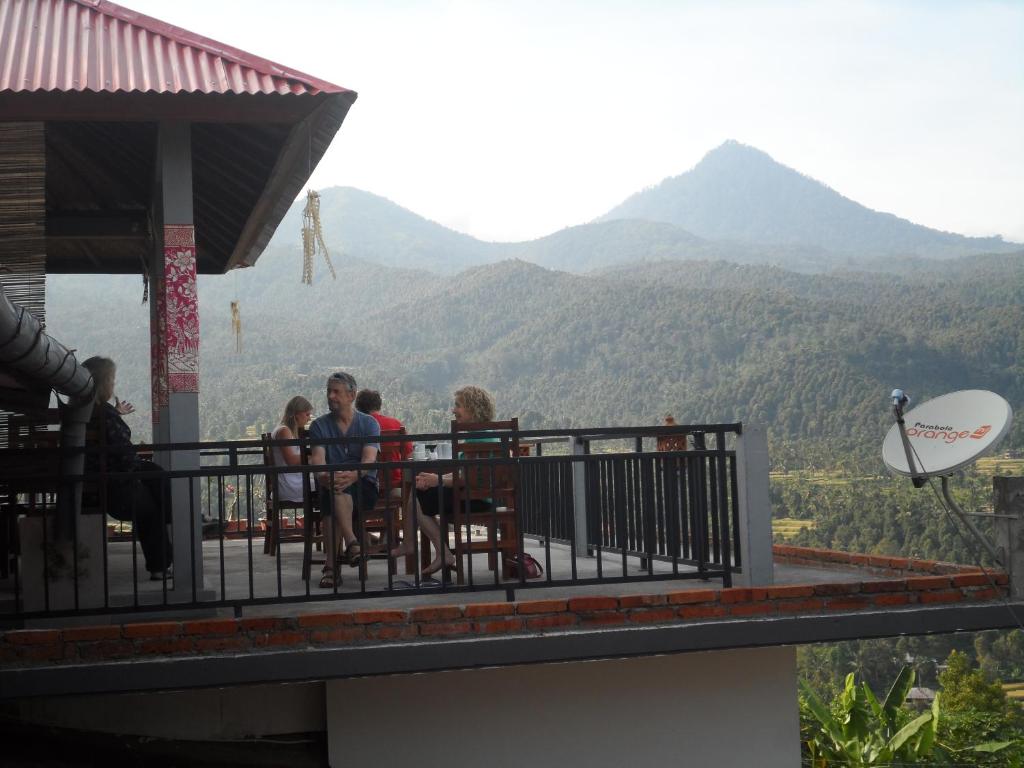 a group of people sitting on a balcony looking at the mountains at One Homestay and Warung in Munduk
