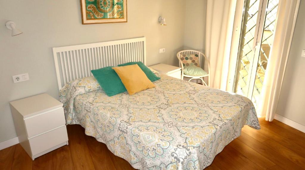 a bedroom with a bed with green and yellow pillows at Sevilla Alameda PG Apartamentos in Seville