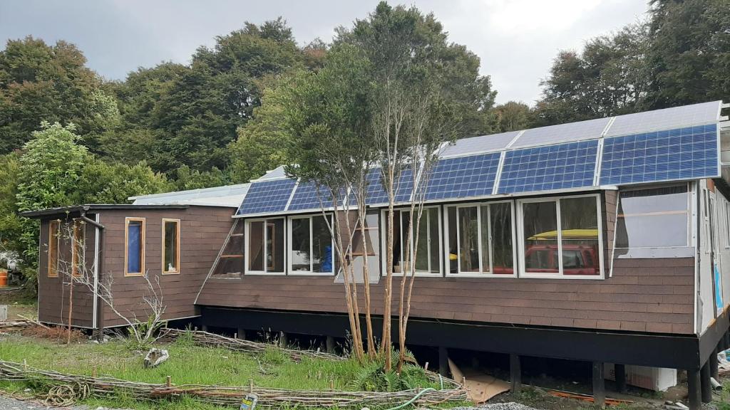 uma casa com painéis solares por cima em Hostal La Minga em Chaitén