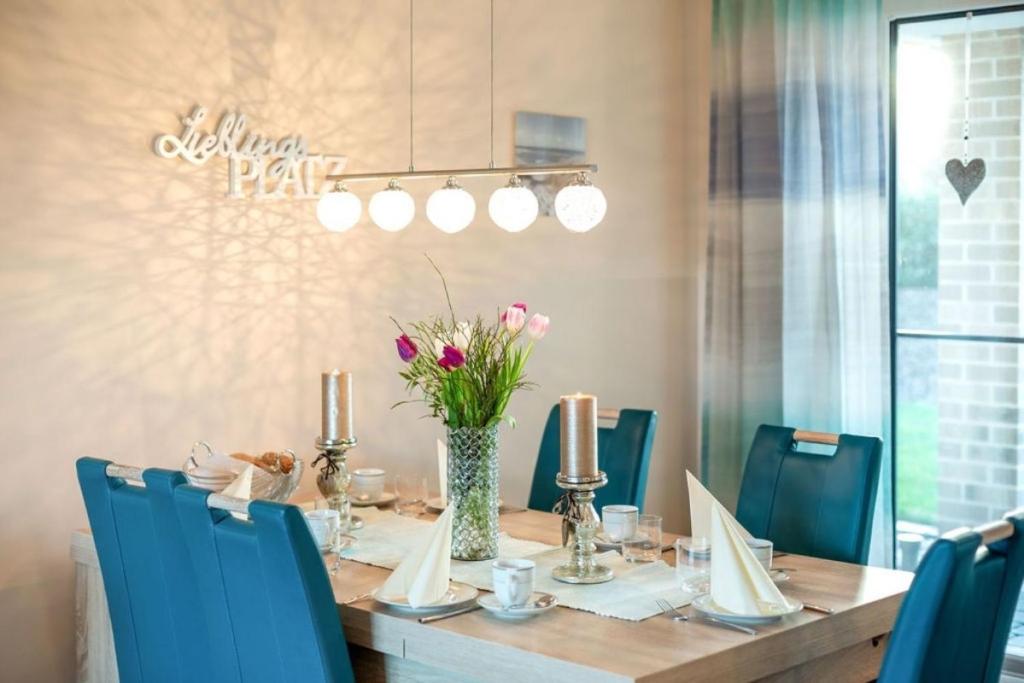 una mesa de comedor con sillas azules y un jarrón de flores en Wellness - Ferienhaus Ostküste, en Klausdorf