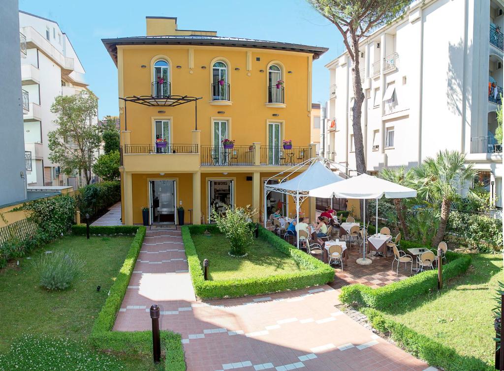 - une vue extérieure sur un bâtiment avec des tables et des chaises dans l'établissement Hotel Alibi, à Rimini