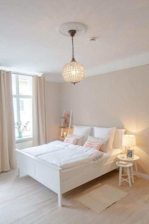 a white bedroom with a white bed and a chandelier at Apartment No3 in Stralsund