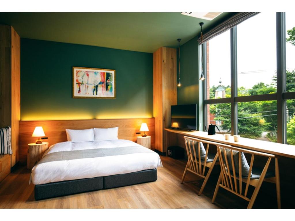 HOTEL KARUIZAWA CROSS - Vacation STAY 56407v في كارويزاوا: غرفة نوم بسرير ونافذة كبيرة
