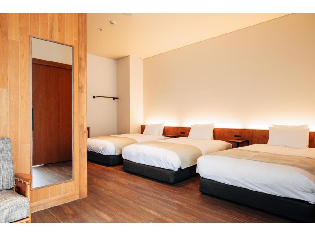 a hotel room with three beds and a mirror at HOTEL KARUIZAWA CROSS - Vacation STAY 56467v in Karuizawa