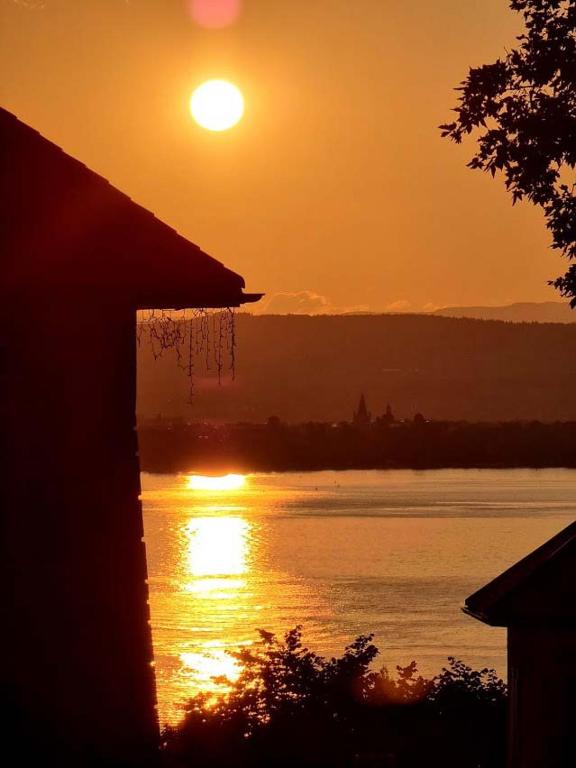 a sunset over a body of water with the sun at Hôtel Restaurant Villa Riva in Veyrier-du-Lac