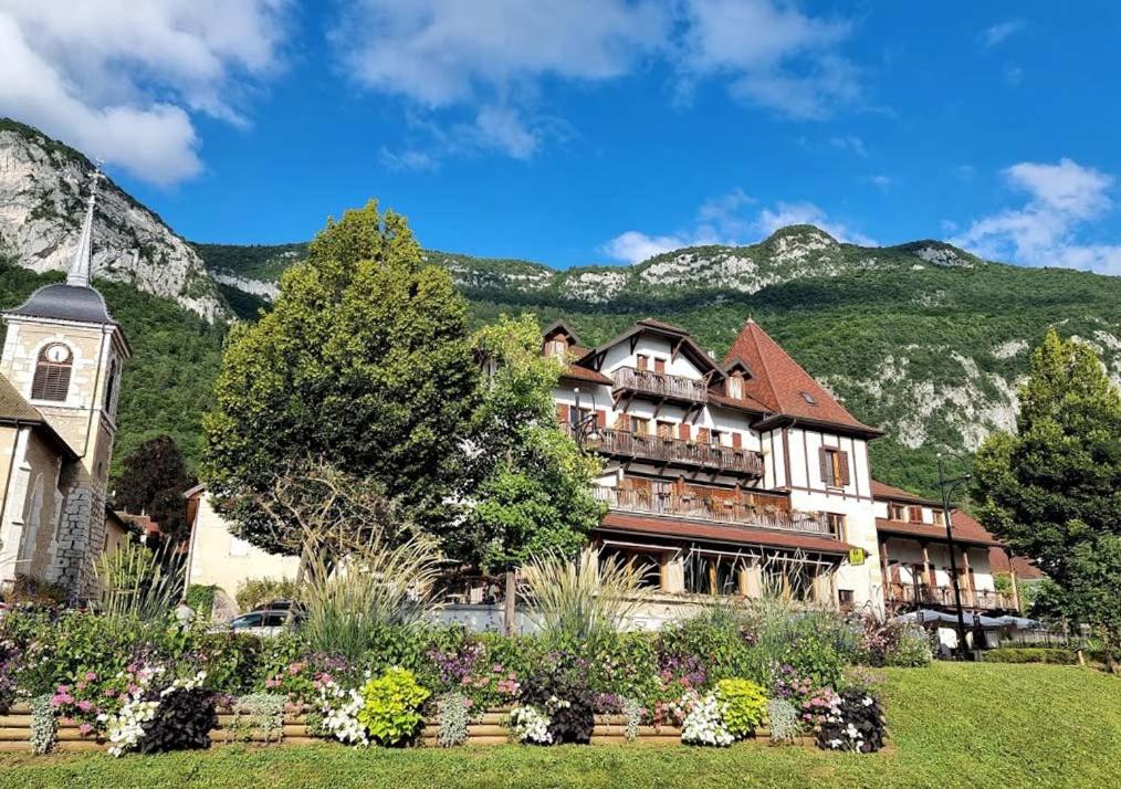 un edificio con una torre dell'orologio di fronte a una montagna di Hôtel Restaurant Villa Riva a Veyrier-du-Lac