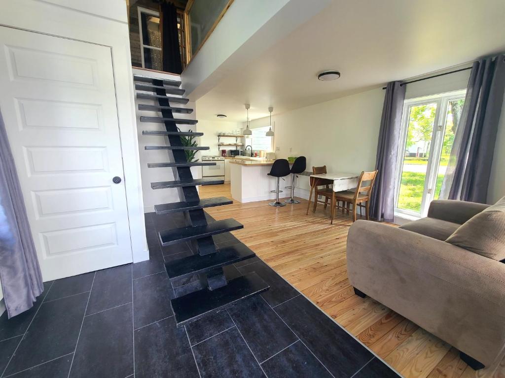 a living room with a staircase with a couch and a table at Aux 4 vents - Auberg'Inn in Carleton-sur-Mer
