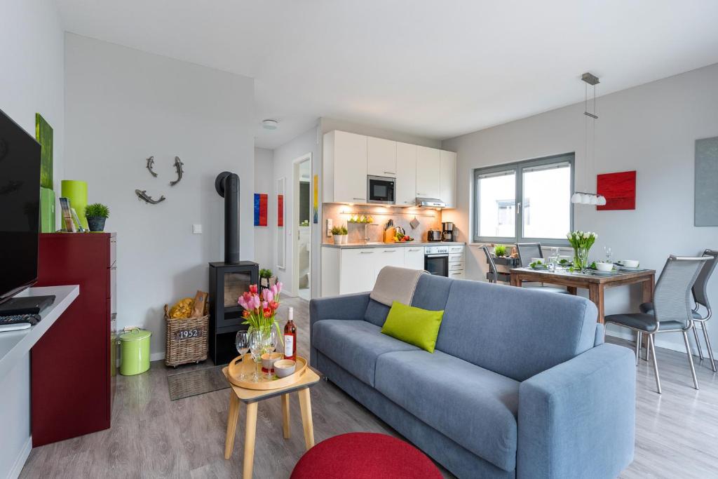 a living room with a blue couch and a kitchen at Ostsee - Appartement "Promenade74" im Strand Resort in Heiligenhafen