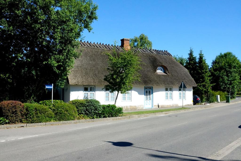 uma casa branca com um telhado de palha numa rua em Paulsen Häuschen - Schloss Gelting em Gelting
