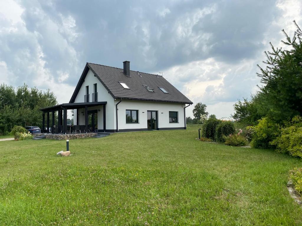 a house with a large yard with a green field at Biały Dom nad jeziorem Rajgrodzkim in Krzywe