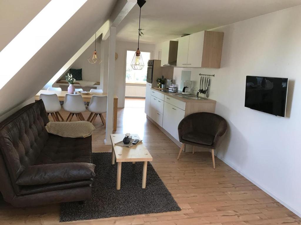 a living room with a couch and a kitchen at Nordische Ferienwohnung auf Gut Bennewohld LL in Heide