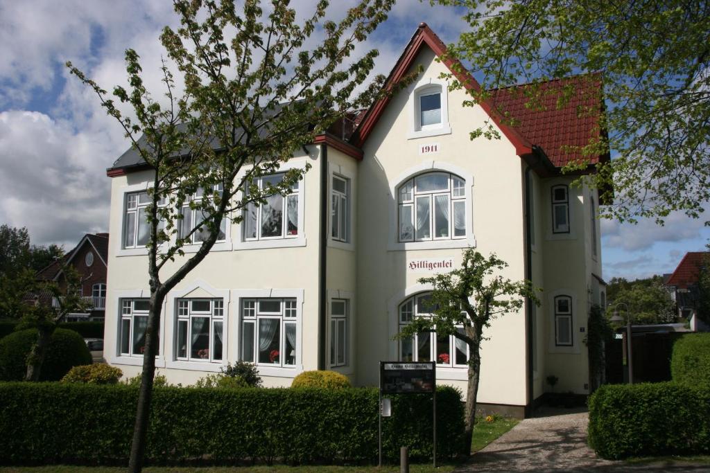 ein weißes Haus mit rotem Dach in der Unterkunft Pension Hilligenlei Zi 06 DZ in Wyk auf Föhr