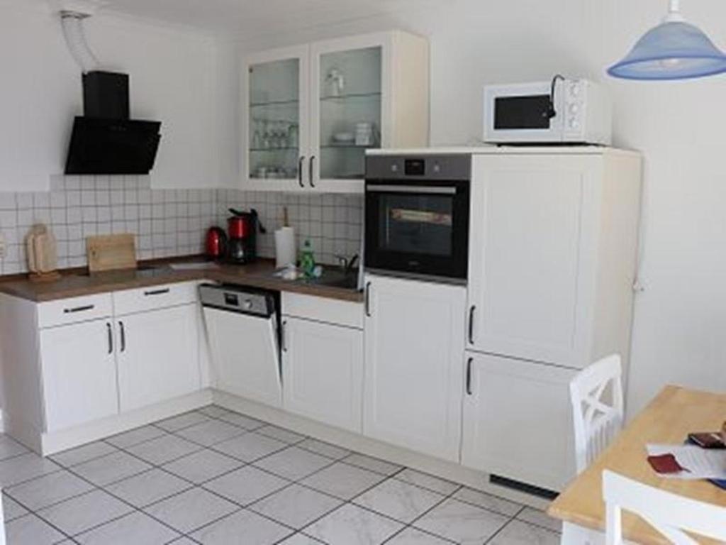 a kitchen with white cabinets and a white refrigerator at Ferienwohnung 1066 App 1 in Tossens in Butjadingen OT Tossens