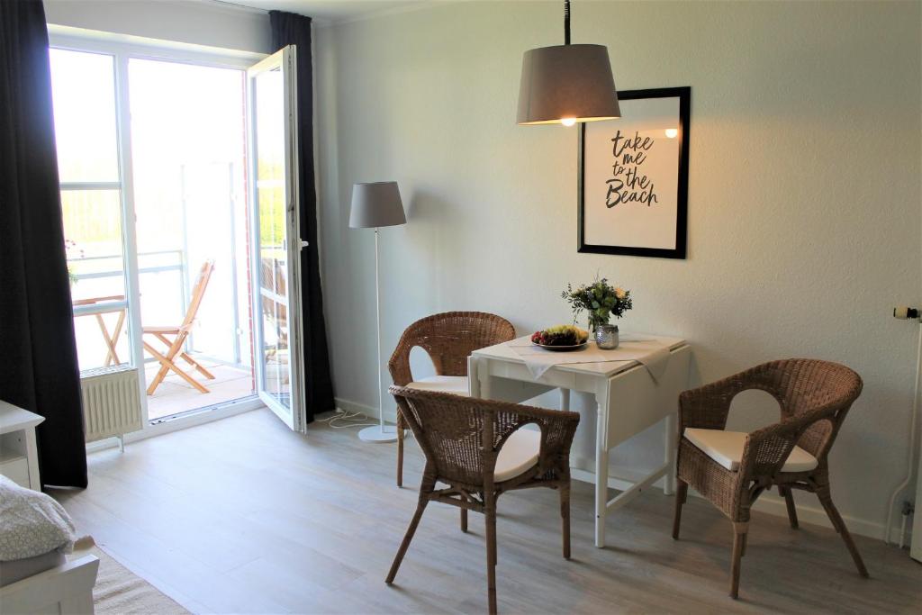 uma sala de jantar com uma mesa e cadeiras brancas e uma janela em "Pappelhof - Whg 10" em Grömitz