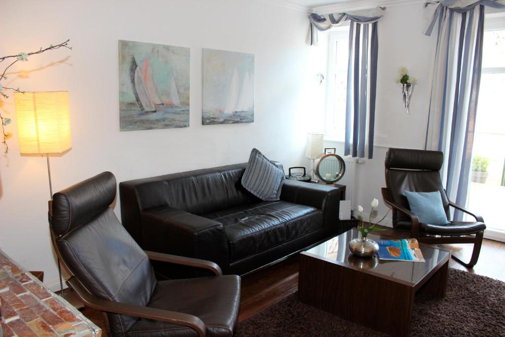 a living room with a black leather couch and chairs at LANDHAUS AM HAFEN im EG in Heiligenhafen