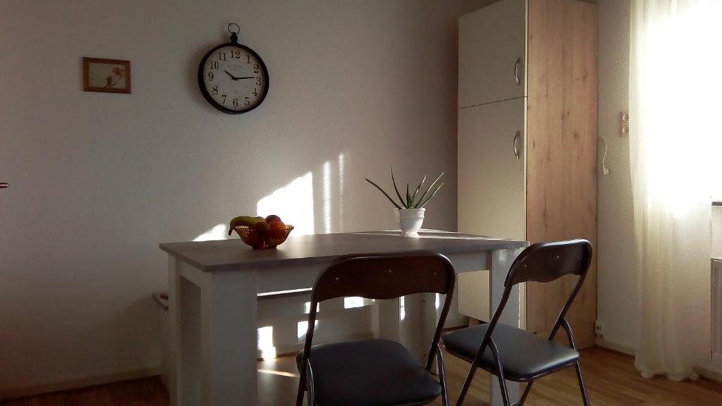 una mesa con dos sillas y un reloj en la pared en Ferienwohnung Klein am Natursteig Sieg, en Bitzen