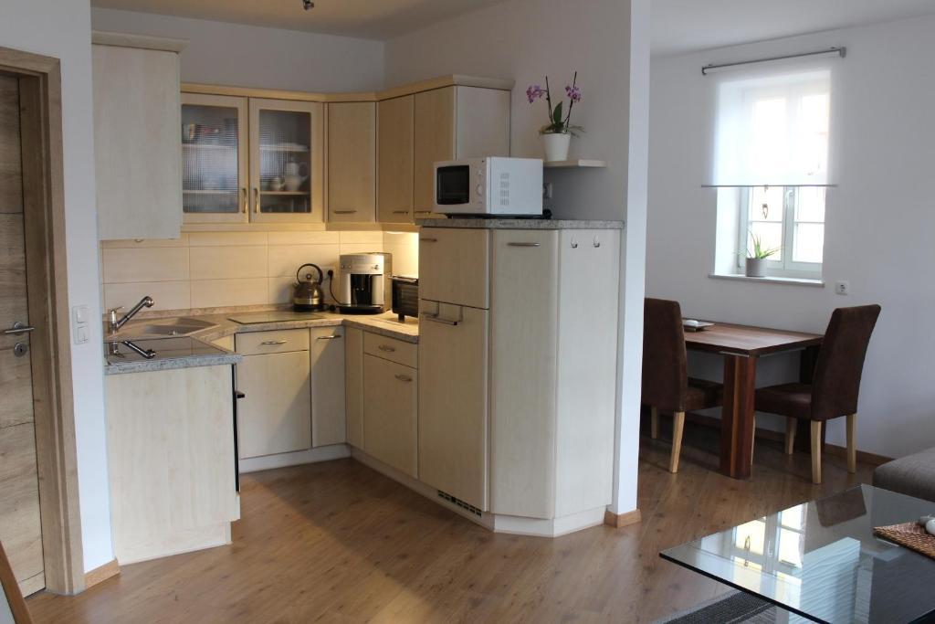 a kitchen with white cabinets and a table with a microwave at Ferienwohnung "Zum Schloßkeller" in Wolkenstein