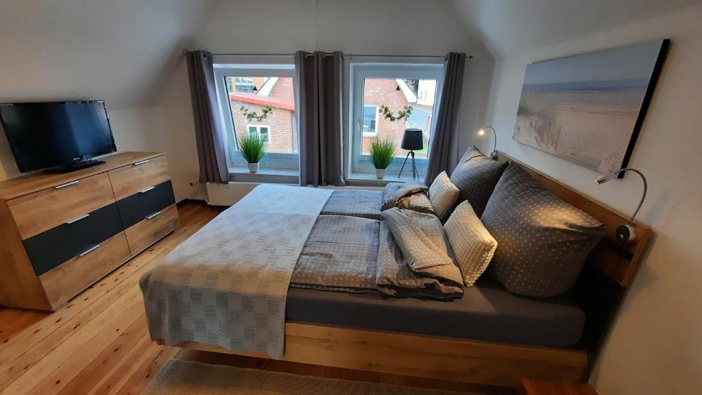Schlafzimmer mit einem Bett, einem TV und einem Fenster in der Unterkunft De Lüdde Mangelstuv in Bredstedt