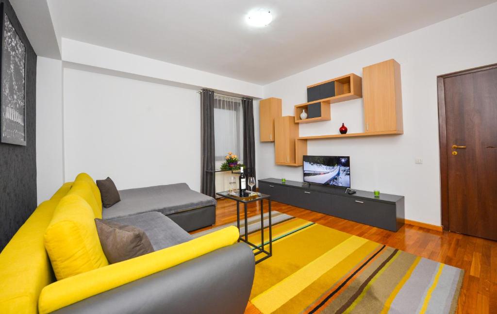 salon z żółtą kanapą i telewizorem w obiekcie Residenza Don Pepito w Bukareszcie