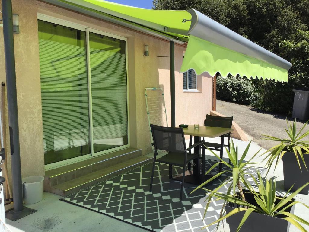 a patio with a table and a green umbrella at Pavillon T2 proche ville dans petite résidence in Cuttoli-Corticchiato