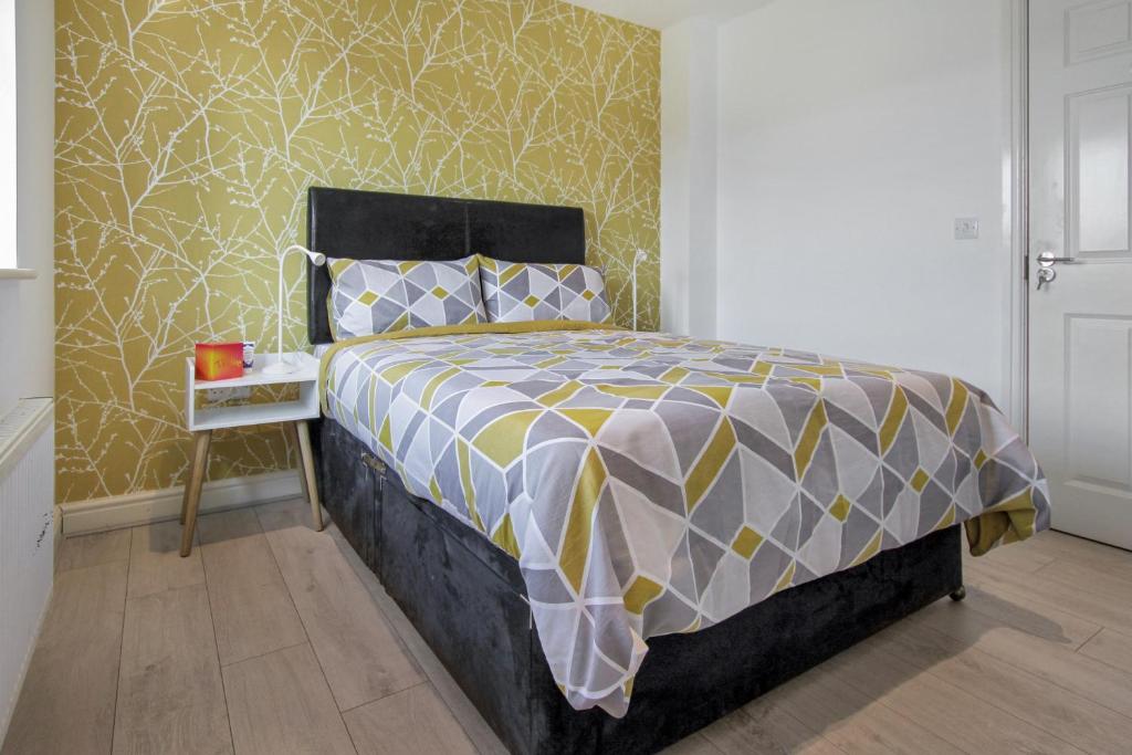 a bedroom with a bed with a yellow and grey comforter at Emerald En-suite in Derby in Derby