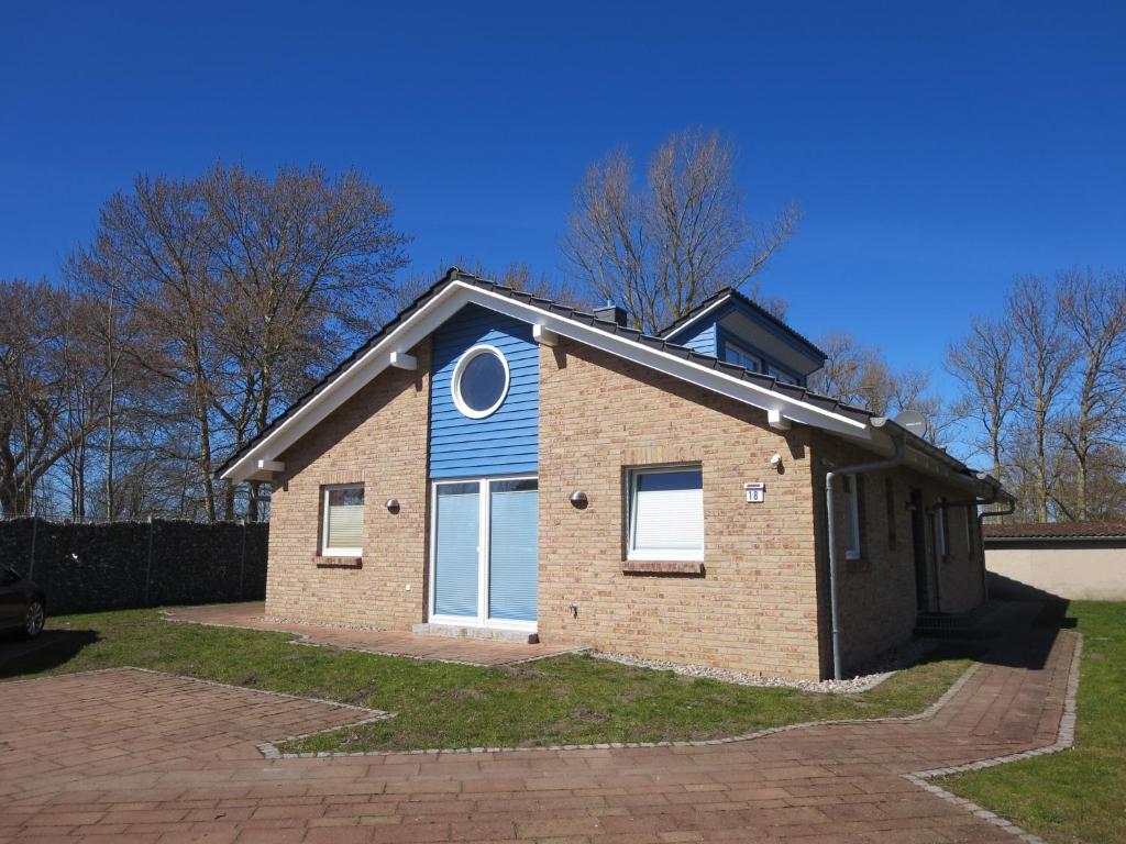 ein kleines Backsteinhaus mit blauem Dach in der Unterkunft Boddenhus in Bresewitz