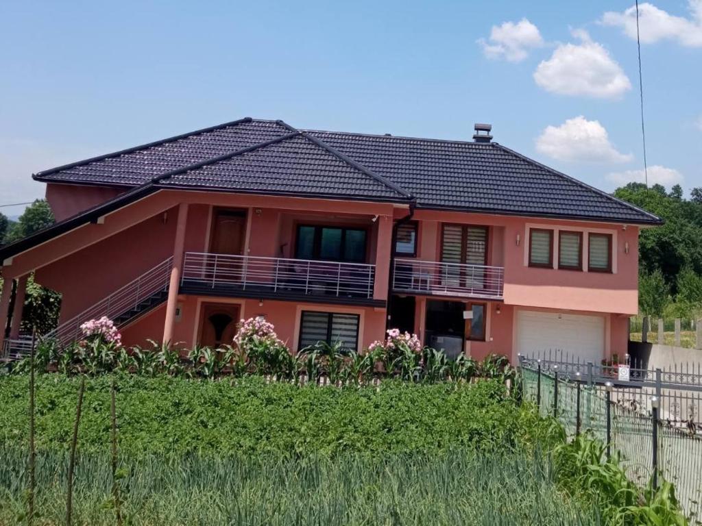 une maison rouge avec une clôture devant elle dans l'établissement Guest House Ahmo Halilcevic, à Dubrave Gornje