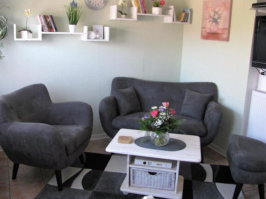 エッカーンフェルデにあるDaniel-Ferienhaus 1のリビングルーム(椅子2脚、花のテーブル付)