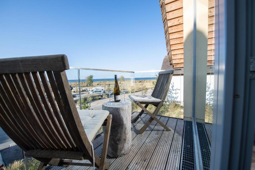 a balcony with two chairs and a bottle of wine at Ostsee - Reetdachhaus Nr 32 "Sonnendeck" im Strand Resort in Heiligenhafen