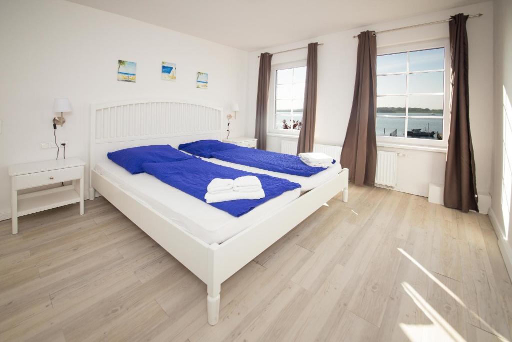 a bedroom with a white bed with blue sheets at Schleiblick App 11 in Rabenkirchen-Faulück
