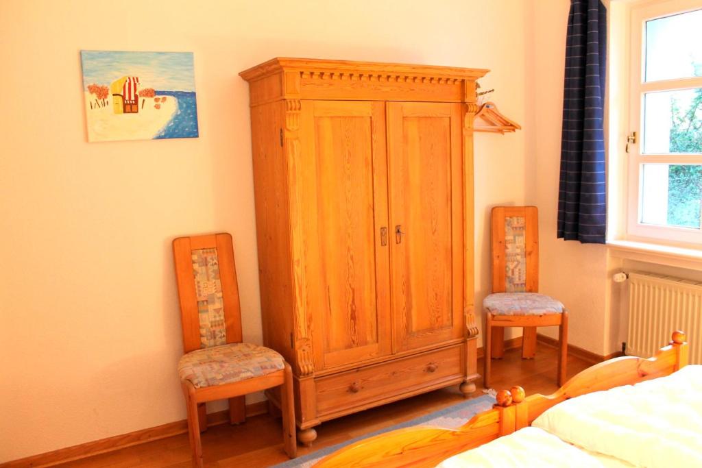 a bedroom with a wooden cabinet and two chairs at Finke-Ferienhaus - EG in Grömitz