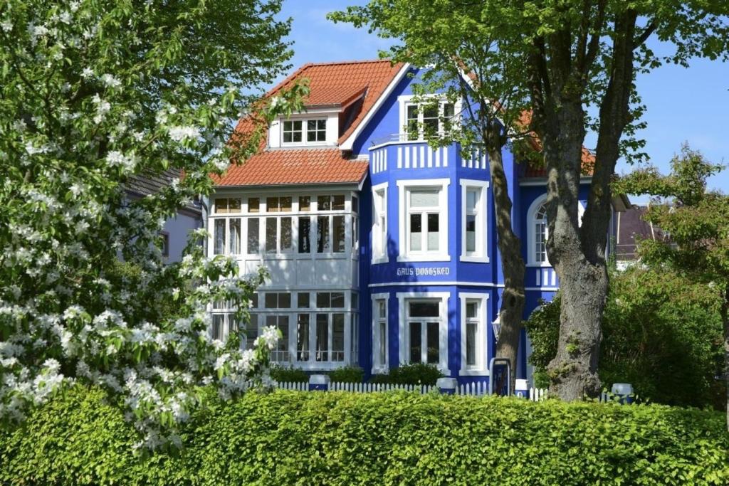 ヴィーク・アウフ・フェールにあるHaus Poggfred Whg 04 Harmensの白い窓と木々のある青い家
