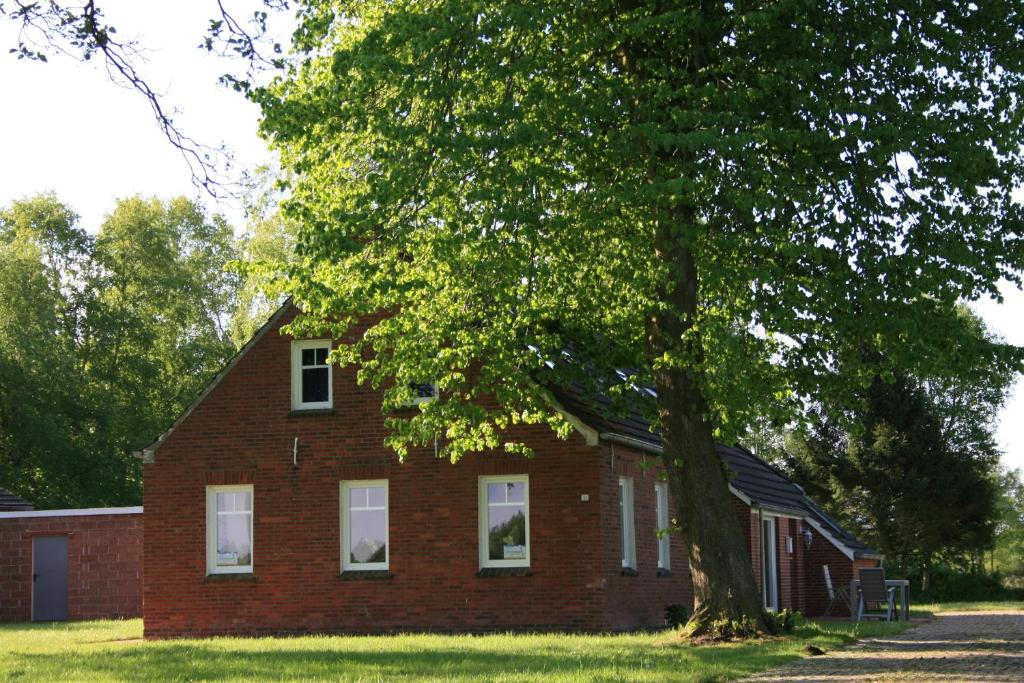 une maison en briques rouges avec un arbre en face de celle-ci dans l'établissement Haus Linden, à Hage