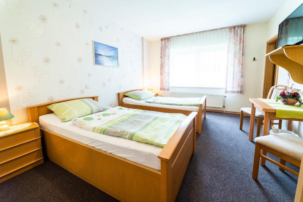 a bedroom with two beds and a table and a desk at Gästezimmer 4 im Landgasthaus Lindenhof in Fresenburg