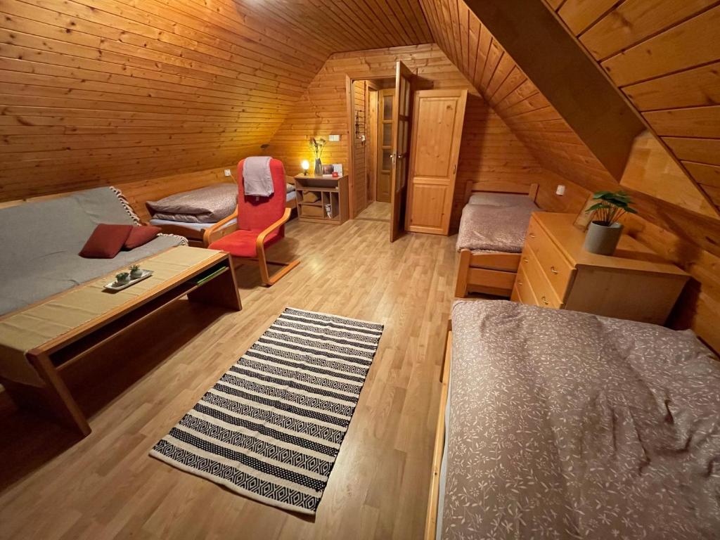 um quarto no sótão com 2 camas, um sofá e uma mesa em Apartmán na hranici em Oravská Polhora