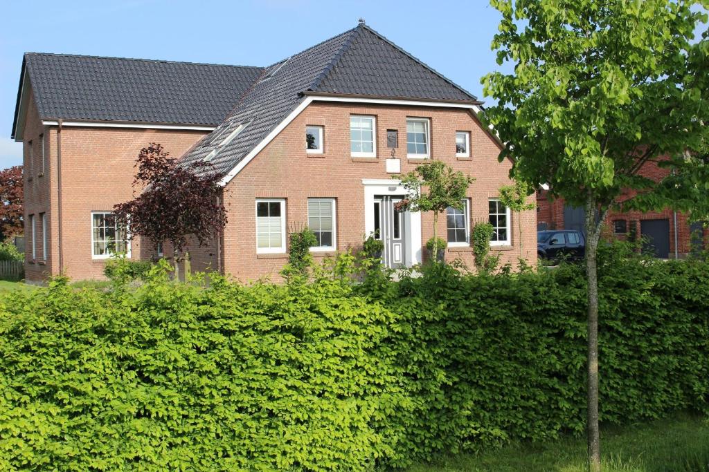 a brick house with a hedge in front of it at Bauernhof Höpner "Im Backhaus" in Vadersdorf