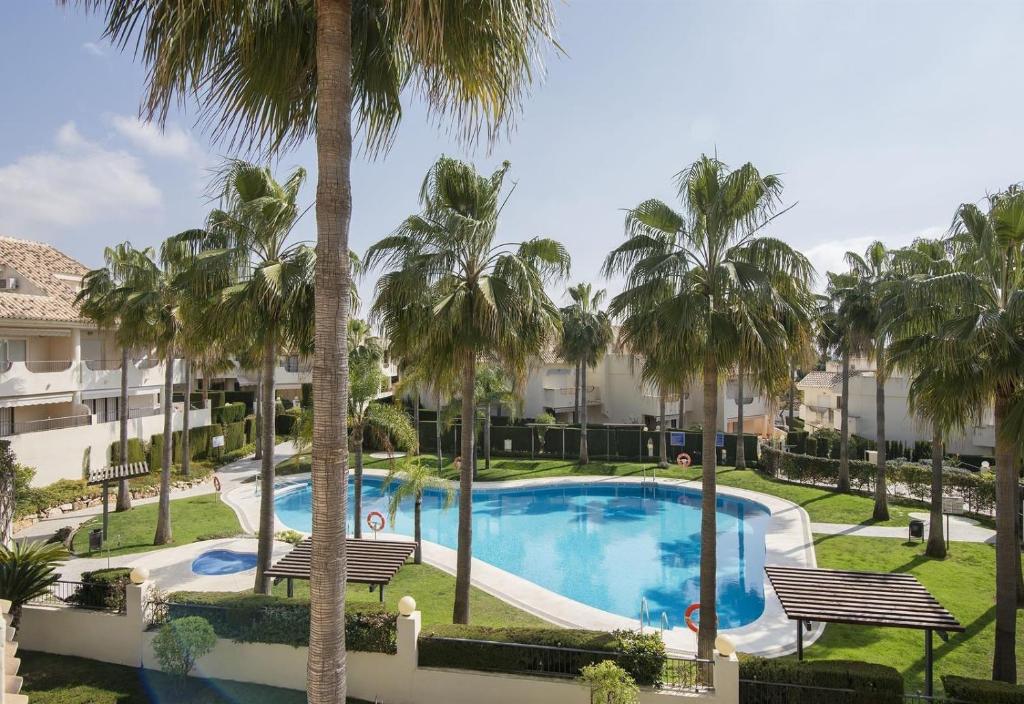 - Vistas a la piscina del complejo, con palmeras en Beautiful townhouse beachfront en Marbella