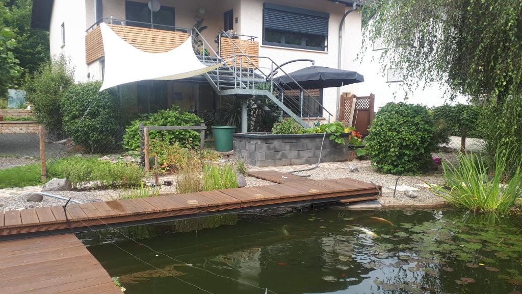 eine Holzbrücke über einen Teich vor einem Haus in der Unterkunft Studio Summer Garden in Trassem