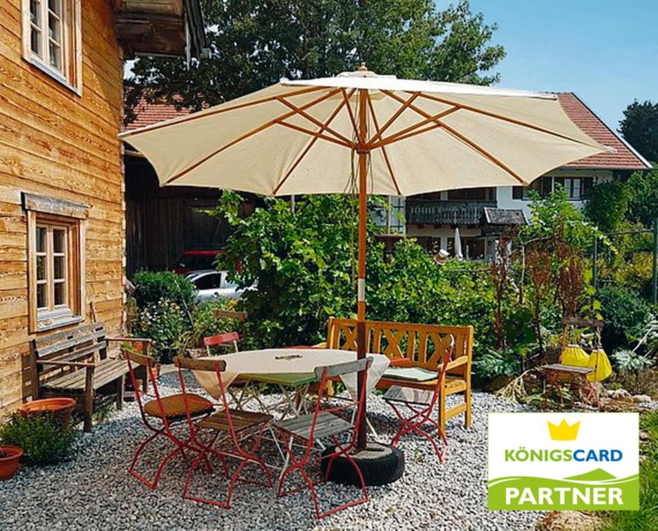 a table and chairs with an umbrella on a patio at Biohof Neihausmo in Böbing