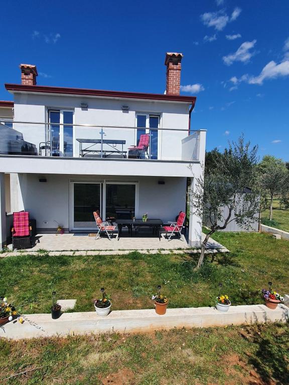 a white house with red chairs and a patio at Olivia Valkanela App 1 in Vrsar